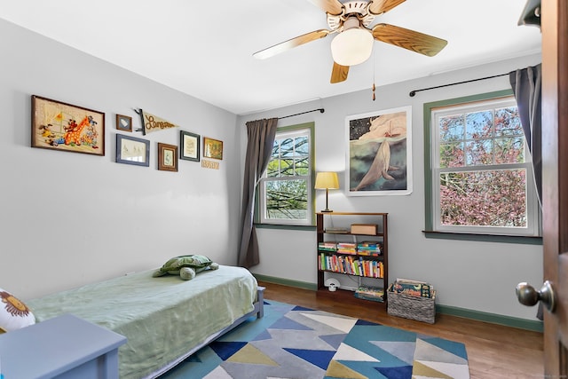 bedroom featuring a ceiling fan, baseboards, and wood finished floors