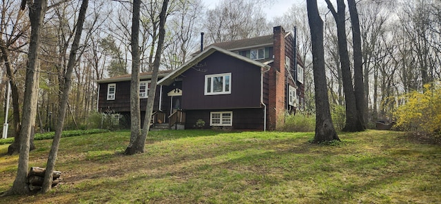raised ranch with a chimney and a front yard