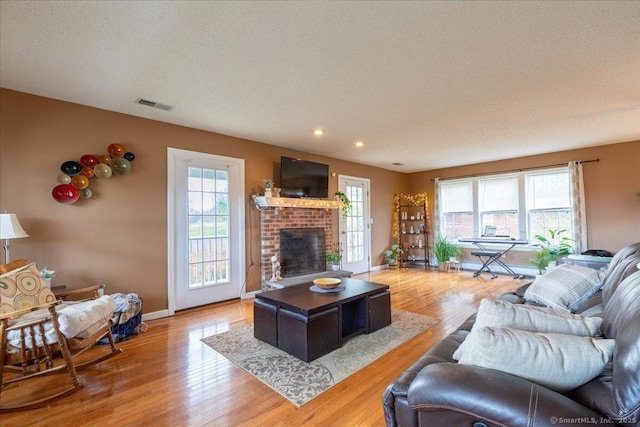 living area with recessed lighting, a fireplace, light wood-type flooring, visible vents, and baseboards