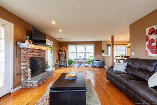 living room featuring a brick fireplace, recessed lighting, wood finished floors, and baseboards