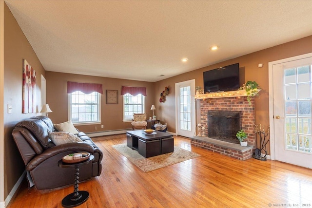 living area featuring recessed lighting, wood finished floors, a baseboard radiator, a brick fireplace, and baseboards