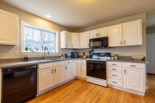 kitchen with black appliances, a sink, and white cabinetry