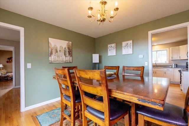 dining room featuring baseboards, light wood finished floors, and a notable chandelier