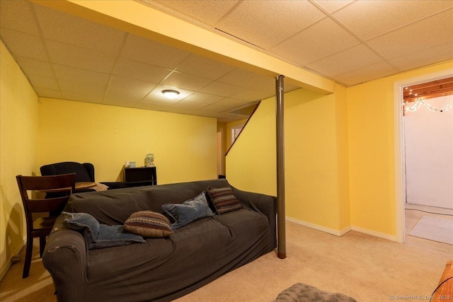 carpeted living room with baseboards and a drop ceiling
