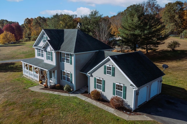view of front facade with covered porch, aphalt driveway, a shingled roof, a front yard, and an attached garage