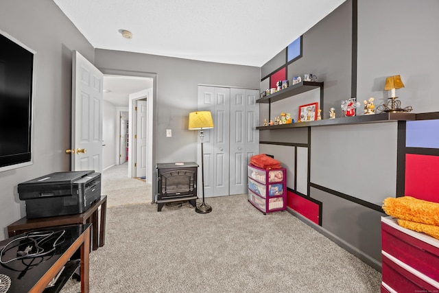 recreation room featuring a wood stove and carpet flooring