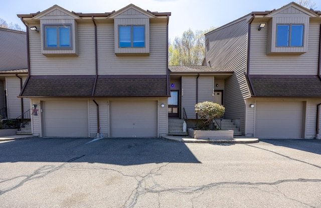 view of front of property with an attached garage, roof with shingles, and aphalt driveway