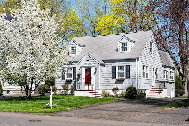 cape cod house with roof with shingles and a front yard