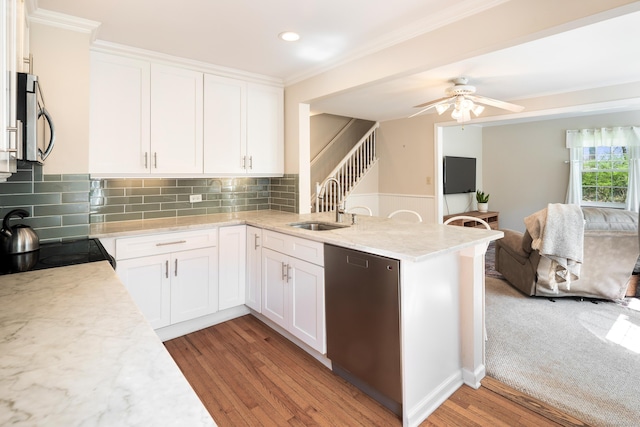 kitchen with appliances with stainless steel finishes, a sink, light wood finished floors, ornamental molding, and white cabinetry
