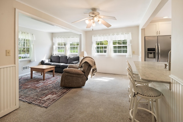 living area featuring ceiling fan, light colored carpet, and visible vents