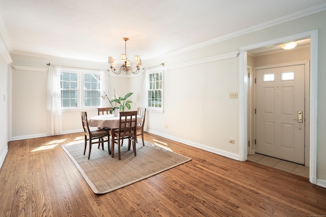 dining area featuring baseboards, ornamental molding, wood finished floors, and a chandelier
