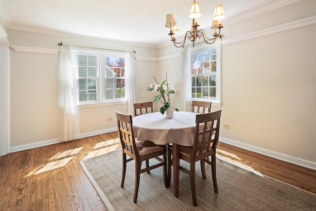 dining room with an inviting chandelier, wood-type flooring, crown molding, and baseboards