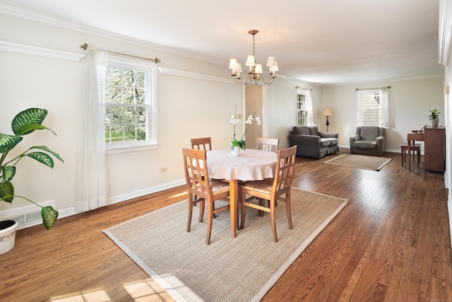 dining space featuring visible vents, ornamental molding, wood finished floors, baseboards, and a notable chandelier