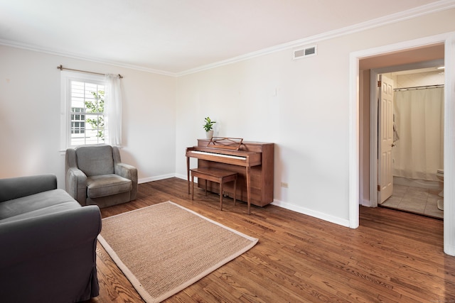 living area with baseboards, ornamental molding, wood finished floors, and visible vents