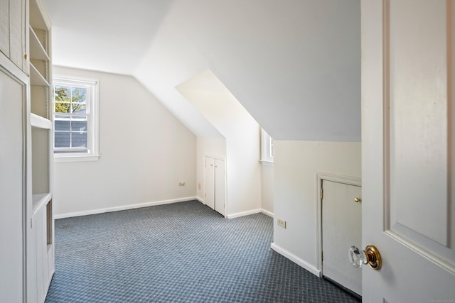 bonus room with baseboards, vaulted ceiling, and dark carpet