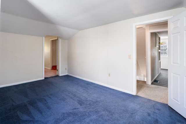 unfurnished bedroom featuring baseboards, dark carpet, and lofted ceiling