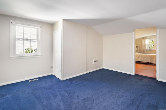 additional living space featuring visible vents, baseboards, and dark colored carpet