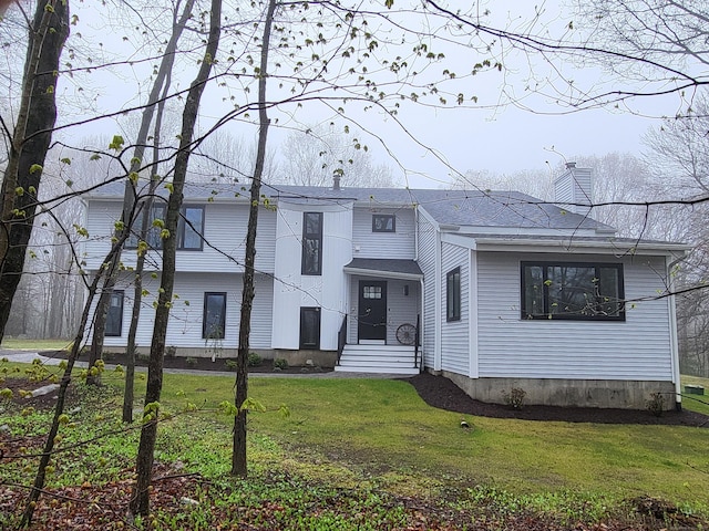 split level home featuring a chimney and a front lawn