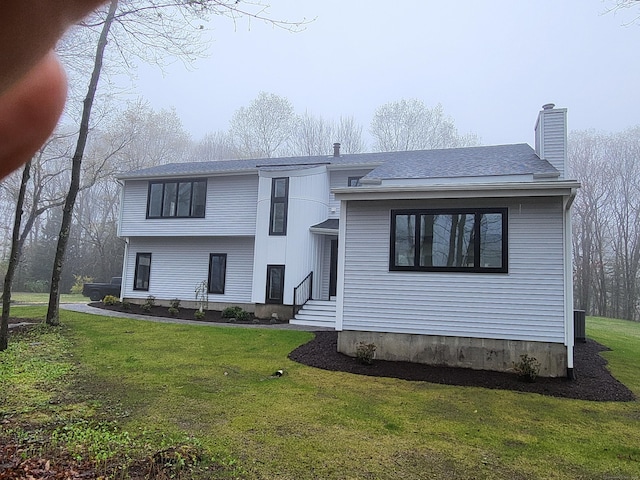 tri-level home with a chimney, a shingled roof, and a front lawn