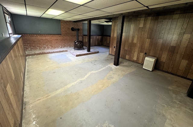 653 Andrew Mountain Rd, Naugatuck, CT 06770 - basement featuring wooden walls, a wood stove, a drop ceiling, and brick wall