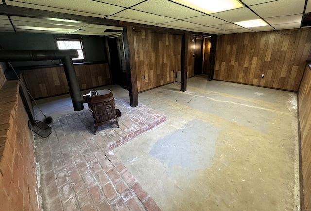 653 Andrew Mountain Rd, Naugatuck, CT 06770 - basement featuring wooden walls, a wood stove, and a paneled ceiling