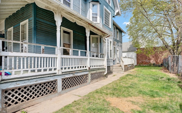 view of side of property featuring fence, a yard, and a porch