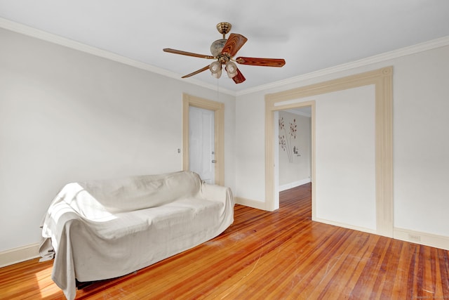 living room with baseboards, hardwood / wood-style flooring, a ceiling fan, and crown molding
