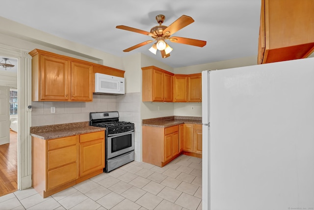 kitchen featuring dark countertops, white appliances, a ceiling fan, and backsplash