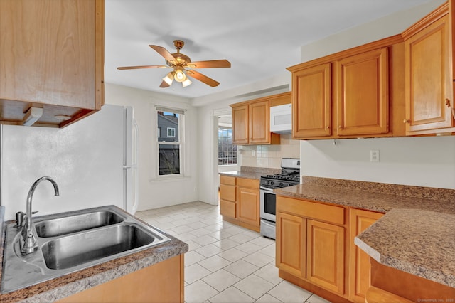 kitchen featuring light tile patterned floors, a sink, white appliances, a ceiling fan, and backsplash
