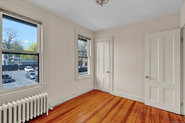 spare room featuring light wood-type flooring, baseboards, and radiator