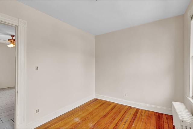 unfurnished room featuring baseboards, radiator heating unit, light wood-type flooring, and ceiling fan