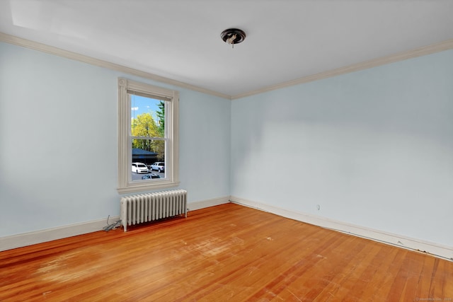 unfurnished room featuring radiator heating unit, light wood finished floors, ornamental molding, and baseboards