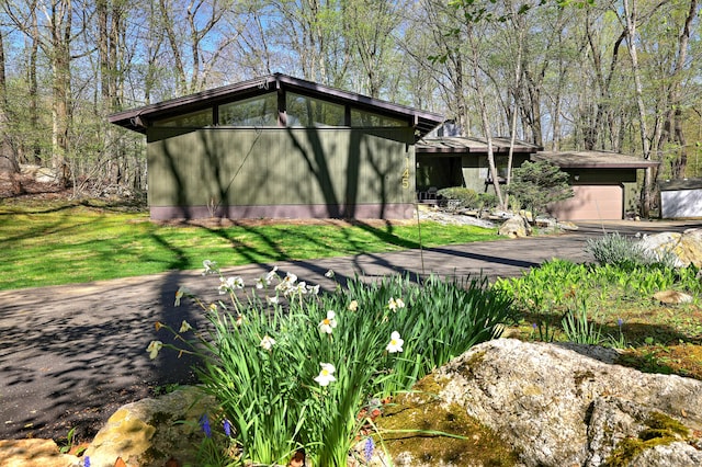 view of front of home featuring a garage, aphalt driveway, and a front yard