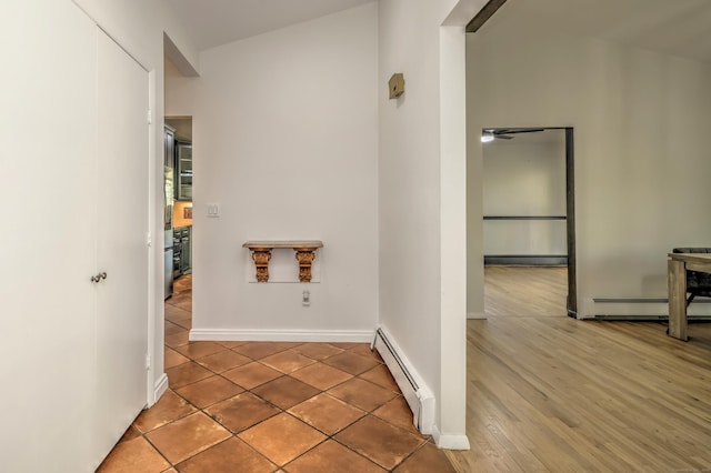 hallway with baseboards, a baseboard heating unit, and tile patterned flooring