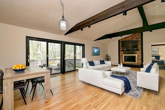 living area with a brick fireplace, a baseboard heating unit, rail lighting, lofted ceiling with beams, and light wood finished floors