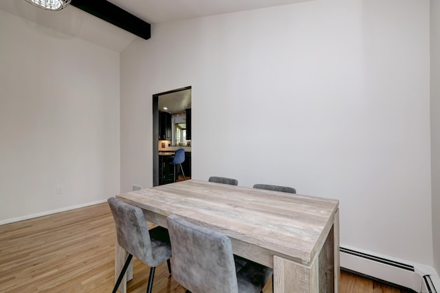dining area with baseboards, vaulted ceiling with beams, baseboard heating, and light wood-type flooring