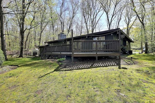 back of house with a wooden deck, a yard, and a chimney