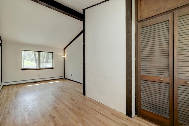 unfurnished bedroom with light wood-style floors, lofted ceiling, and a baseboard heating unit
