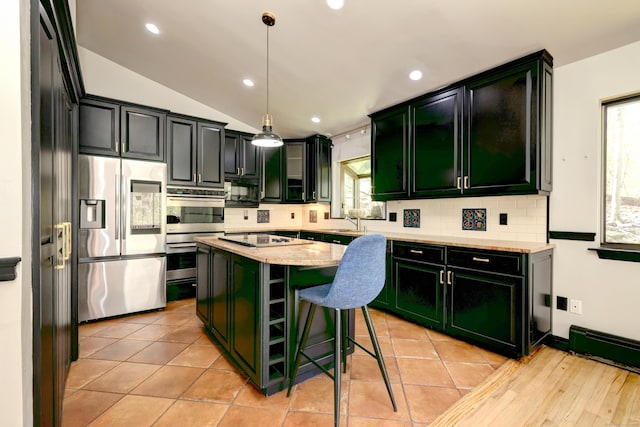 kitchen featuring a sink, stainless steel appliances, backsplash, a kitchen island, and green cabinets