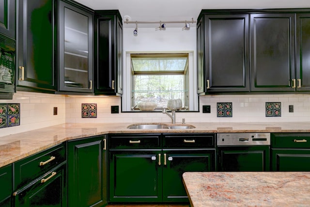 kitchen featuring a sink, decorative backsplash, green cabinets, and light stone countertops