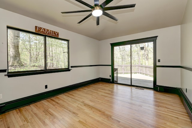spare room with a ceiling fan, a wealth of natural light, and wood finished floors