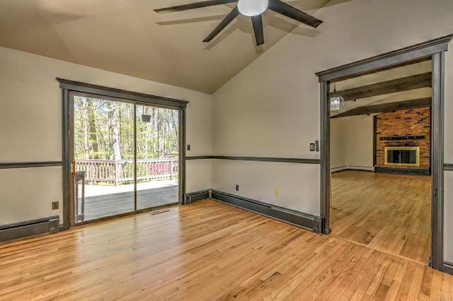 empty room with ceiling fan, visible vents, a brick fireplace, lofted ceiling, and hardwood / wood-style floors