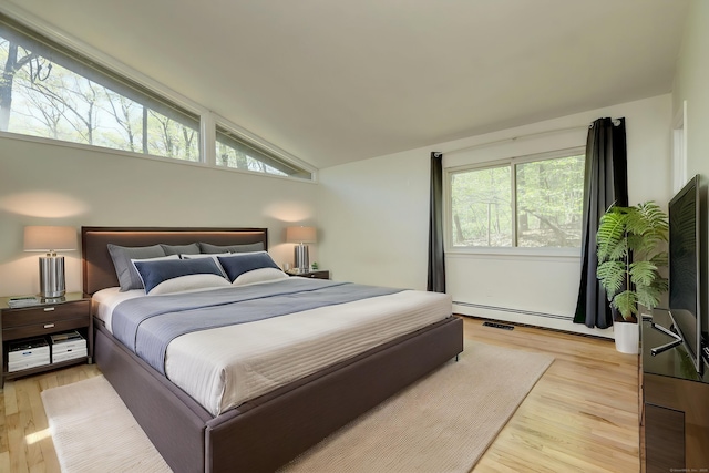 bedroom featuring a baseboard radiator, light wood-type flooring, visible vents, and lofted ceiling