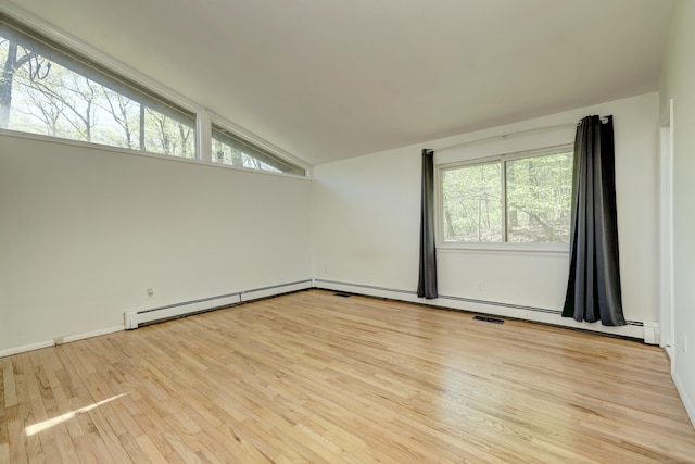 spare room with vaulted ceiling, wood finished floors, visible vents, and a baseboard radiator