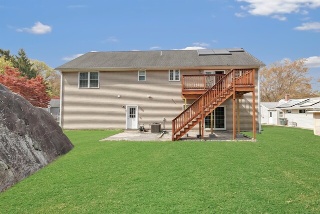rear view of property with a patio, stairway, central AC, a deck, and solar panels