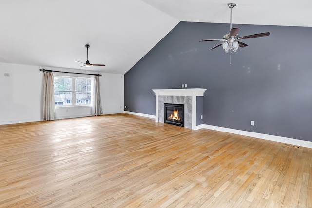 unfurnished living room with a tile fireplace, light wood-type flooring, a ceiling fan, visible vents, and lofted ceiling