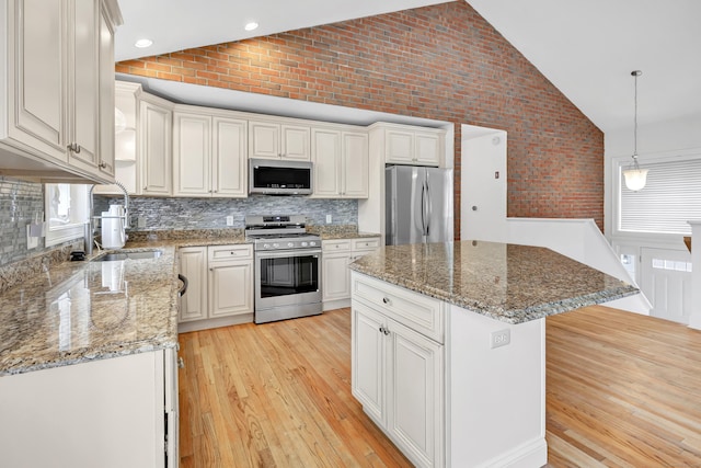 kitchen with light wood finished floors, backsplash, appliances with stainless steel finishes, and a wealth of natural light