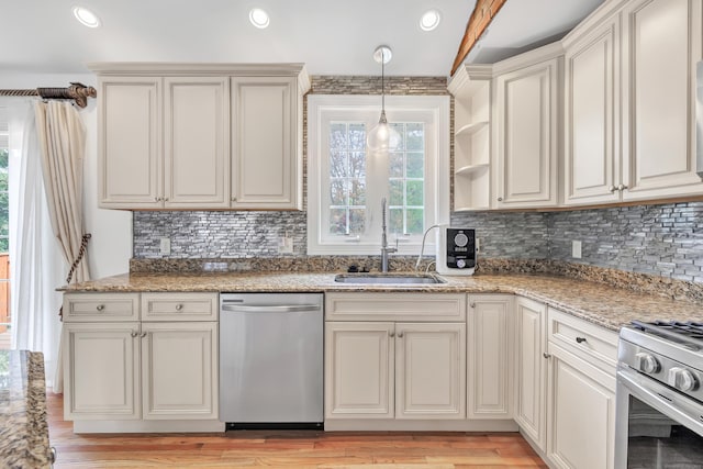 kitchen featuring light wood-style floors, stainless steel appliances, decorative backsplash, and a sink