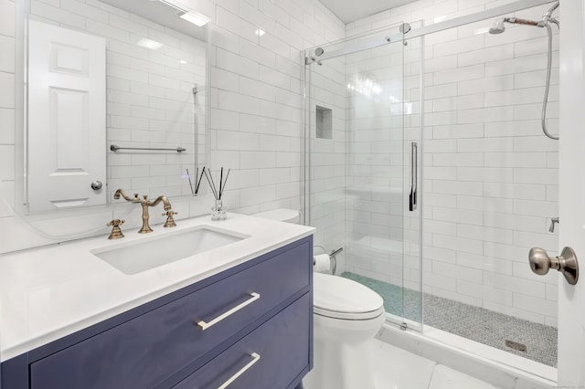 bathroom featuring toilet, a shower stall, and vanity