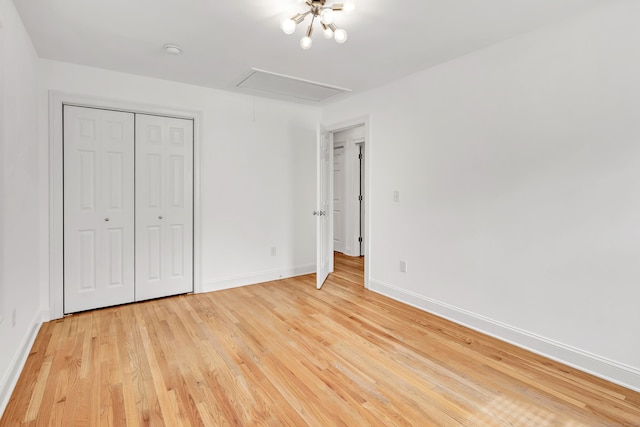 unfurnished bedroom with attic access, light wood-type flooring, a closet, and baseboards